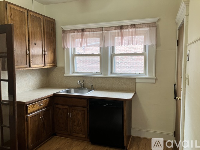 A kitchen with wooden cabinets and a black dishwasher.