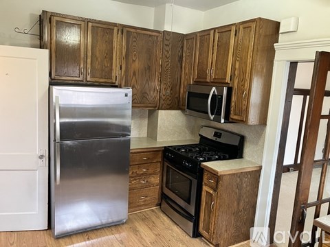 A kitchen with wooden cabinets and a stainless steel refrigerator.