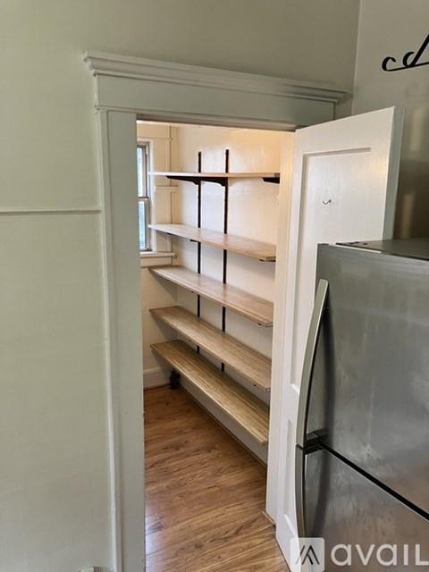 A kitchen pantry with a white door and shelves.