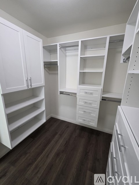 A kitchen with white cabinets and drawers, and a wooden floor.