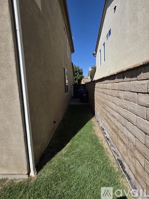 A narrow alley between two buildings with a green lawn on the side.