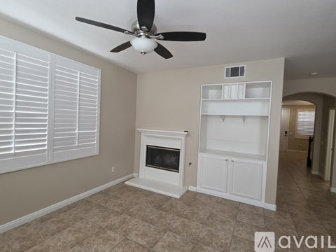 A living room with a fireplace and a fan.