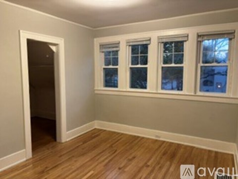 A room with wooden floors and three windows.