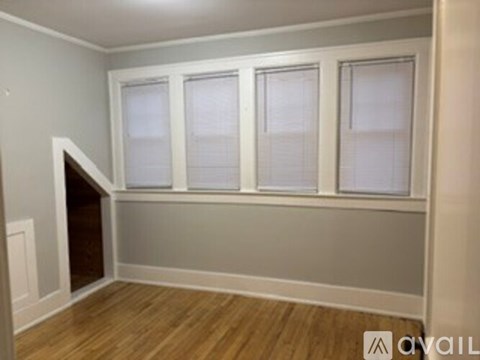 A room with a wooden floor and three windows.