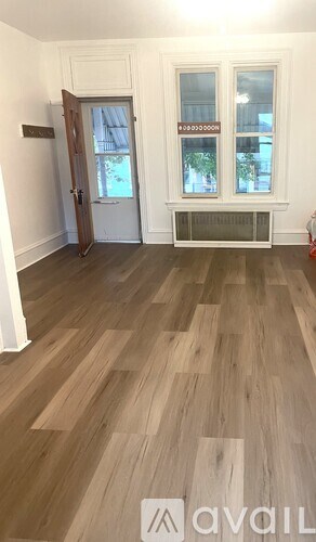 A room with a wooden floor and a window with a view of trees.