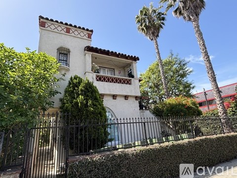 A white house with a red tile roof and a black fence.