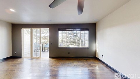 A spacious room with a sliding glass door leading to a balcony.