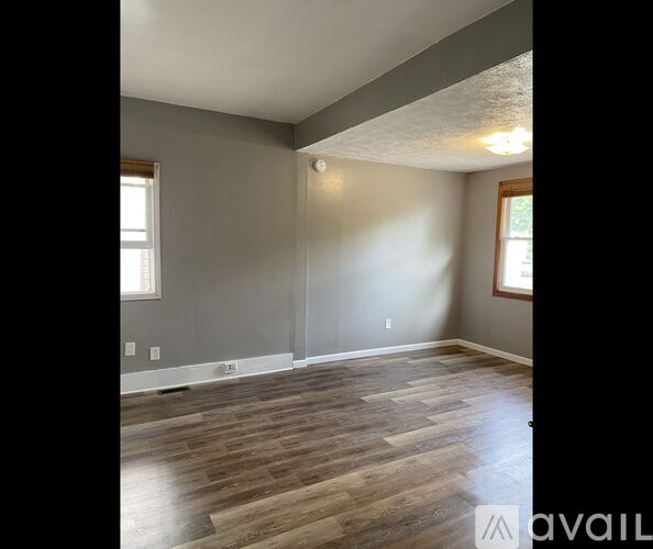 A room with wooden flooring and a window on the left side.