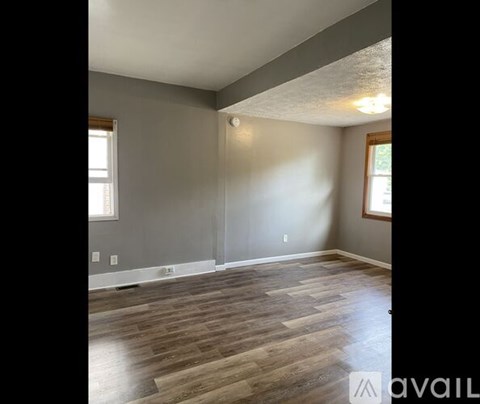 A room with wooden flooring and a window on the left side.