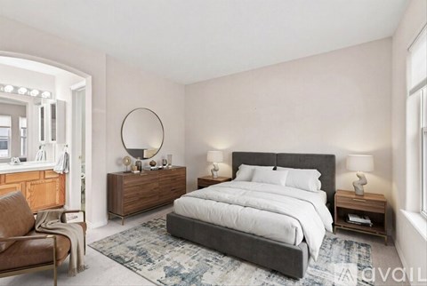 A bedroom with a large bed, a chair, and a dresser with a mirror.