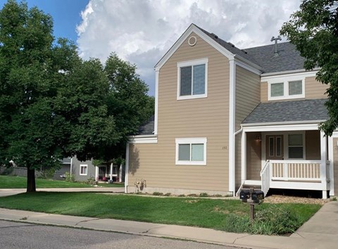 A house with a brown siding and a white porch.