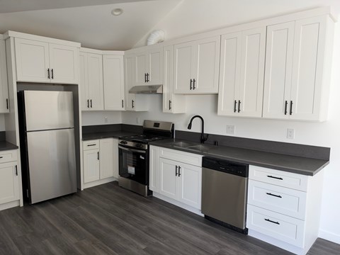 A kitchen with white cabinets and a black countertop.