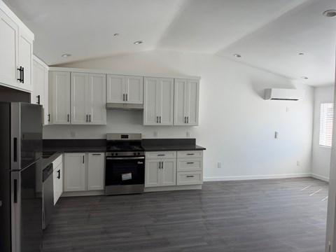 A kitchen with white cabinets and a black countertop.