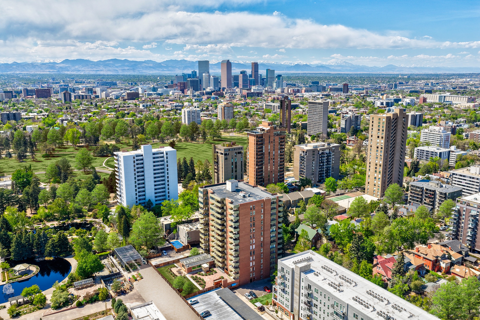 A cityscape with a mix of residential and commercial buildings, surrounded by greenery and a clear sky.