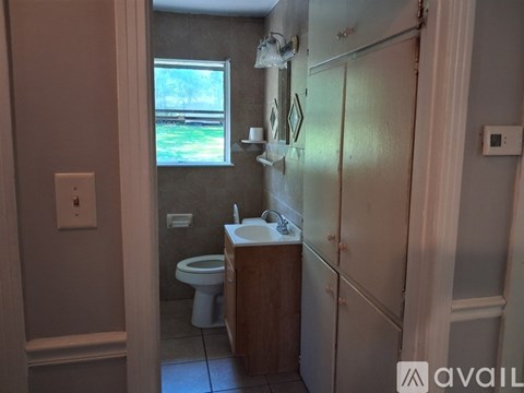 A bathroom with a toilet, sink, and a window.