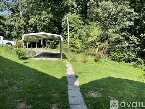 A white canopy structure is situated in a grassy area with a concrete path leading to it.
