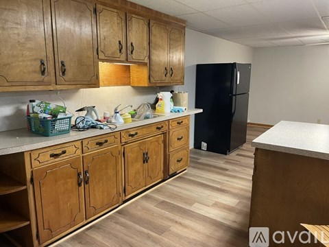 A kitchen with wooden cabinets and a black refrigerator.