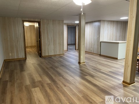 A spacious room with wooden flooring and a white cabinet.