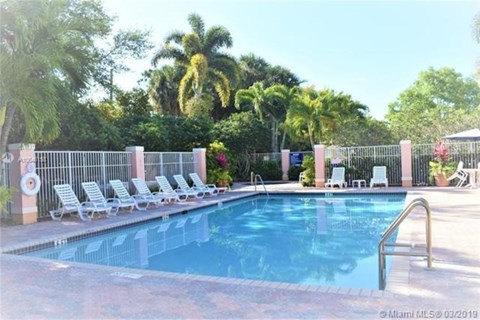 A pool surrounded by palm trees and lounge chairs.