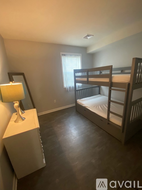 A bedroom with a bunk bed and a nightstand with a lamp.