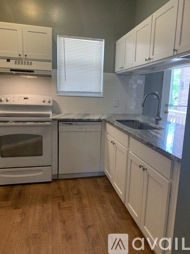 A kitchen with white cabinets and a wooden floor.