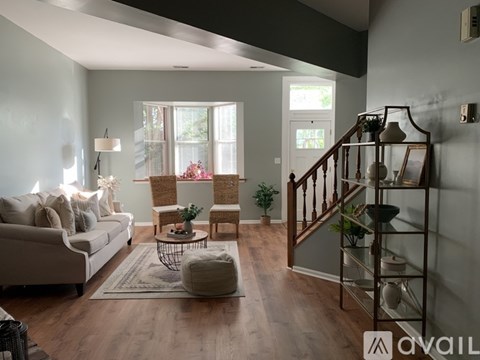 A living room with a white couch, a coffee table, and a staircase.