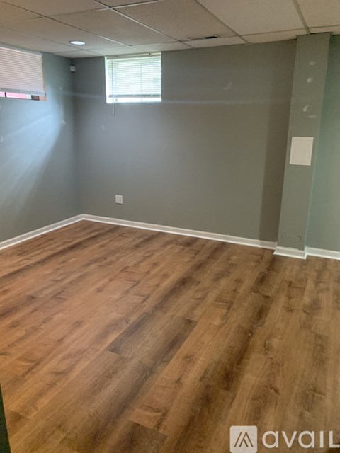 A room with wooden flooring and a window with blinds.