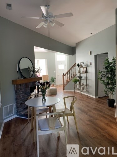 A dining room with a table and chairs and a plant on the side.