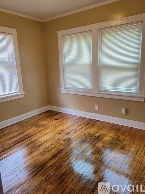 A room with wooden floors and two windows.