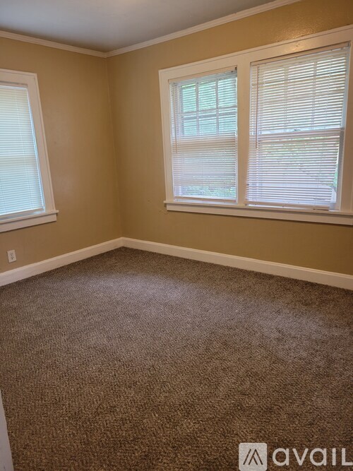 A room with a carpeted floor and two windows.