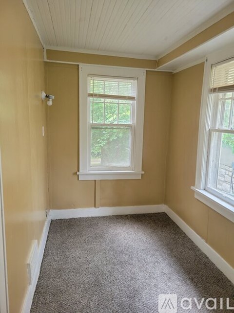 A room with a window and a carpeted floor.