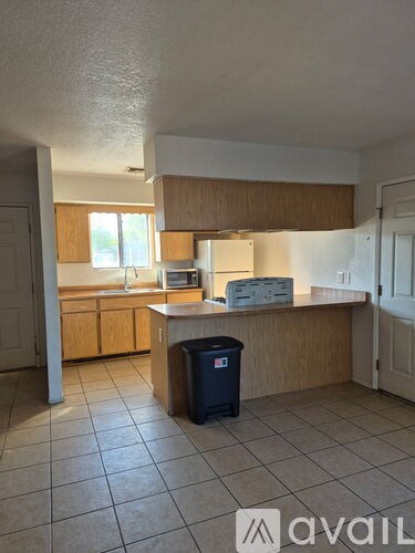 A kitchen with a trash bin in the middle of the room.