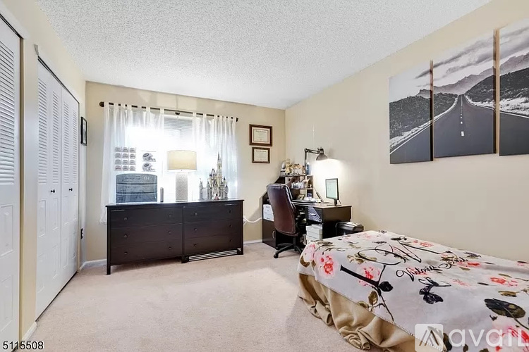 A bedroom with a large bed, a desk with a chair, and a dresser with a mirror.