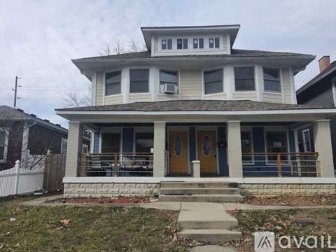 A two-story house with a front porch and a brown door.