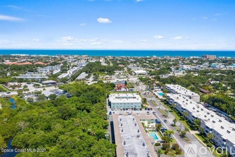 A bird's eye view of a parking lot with a building in the background.