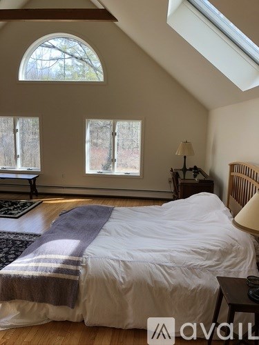 A bedroom with a bed, a nightstand, and a window.