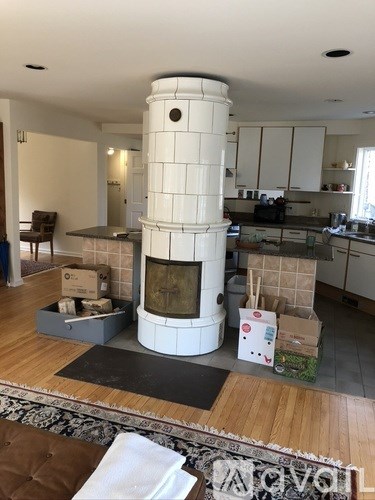 A white fireplace in a room with a brown rug and a wooden floor.
