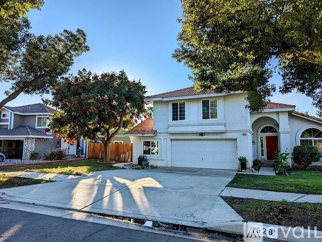 A white two-story house with a red door and garage door.