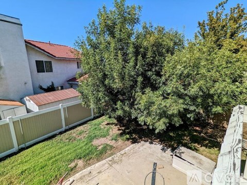 A house with a red roof and a white fence is surrounded by trees.