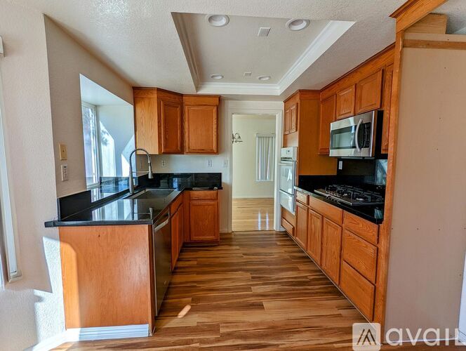 A kitchen with wooden cabinets and black countertops.