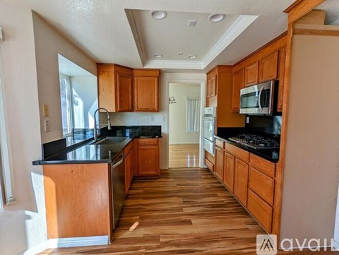 A kitchen with wooden cabinets and black countertops.