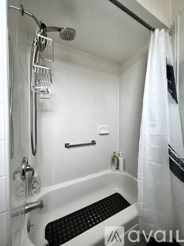 A white bathtub with a shower head and a white shower curtain.