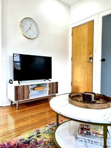 A living room with a flat screen TV and a round table.