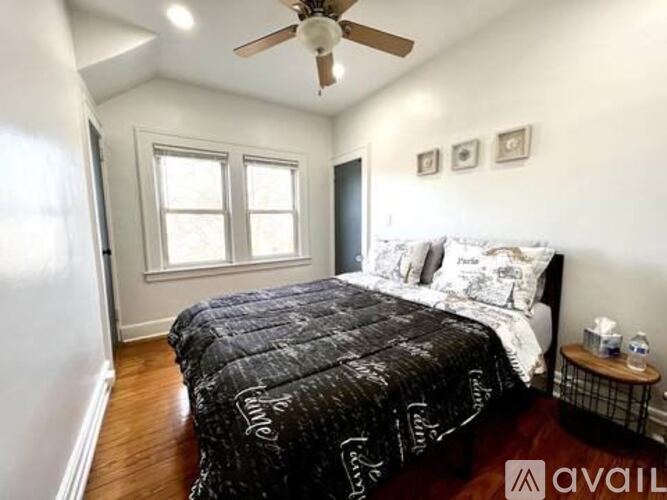 A bedroom with a bed, a ceiling fan, and a window.