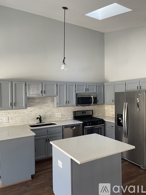 A kitchen with a white counter top and grey cabinets.
