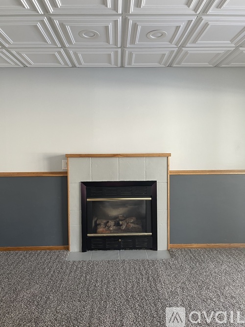 A fireplace with a wooden mantle and a fire burning inside.