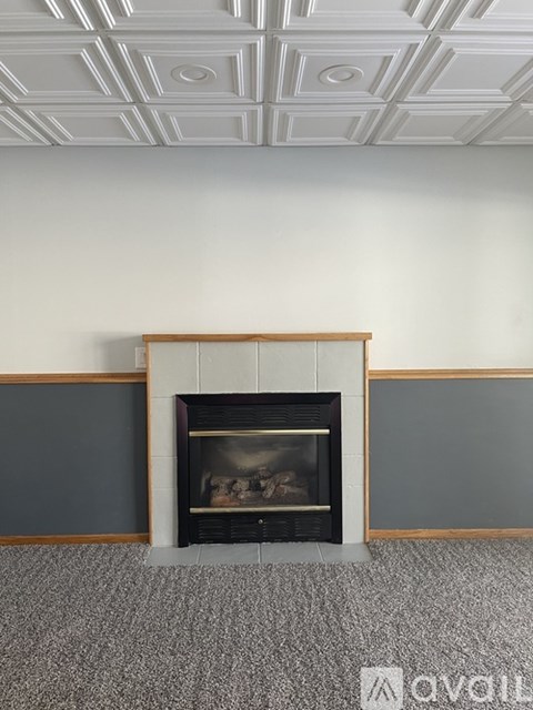 A fireplace with a wooden mantle and a fire burning inside.