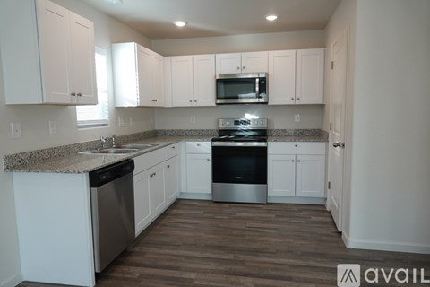 A kitchen with white cabinets and a granite countertop.