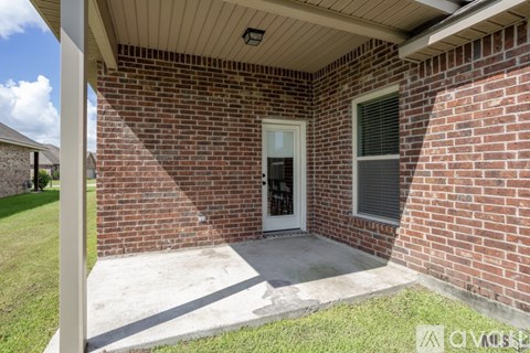 A red brick house with a white door and a small porch.