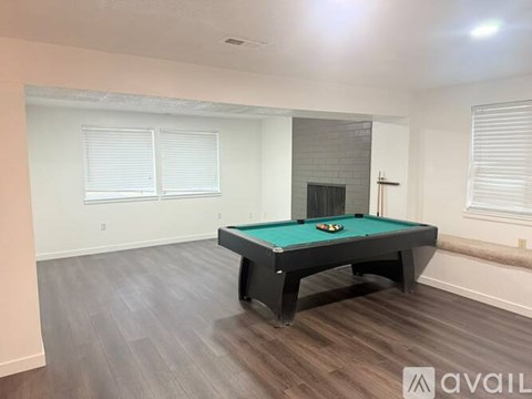 A pool table in a room with light wood flooring and white walls.